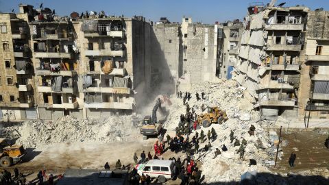 Syrian soldiers look on as rescuers use heavy machinery to sift through the rubble of a collapsed building in the northern city of Aleppo. 