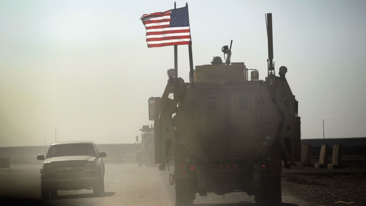 A US Army armored vehicle in Iraq provides security escort on December 2, 2011, for a convoy pulling equipment that is heading to Kuwait from Camp Adder as the Army sends soldiers and equipment home and the base is prepared to be handed back to the Iraqi government.
