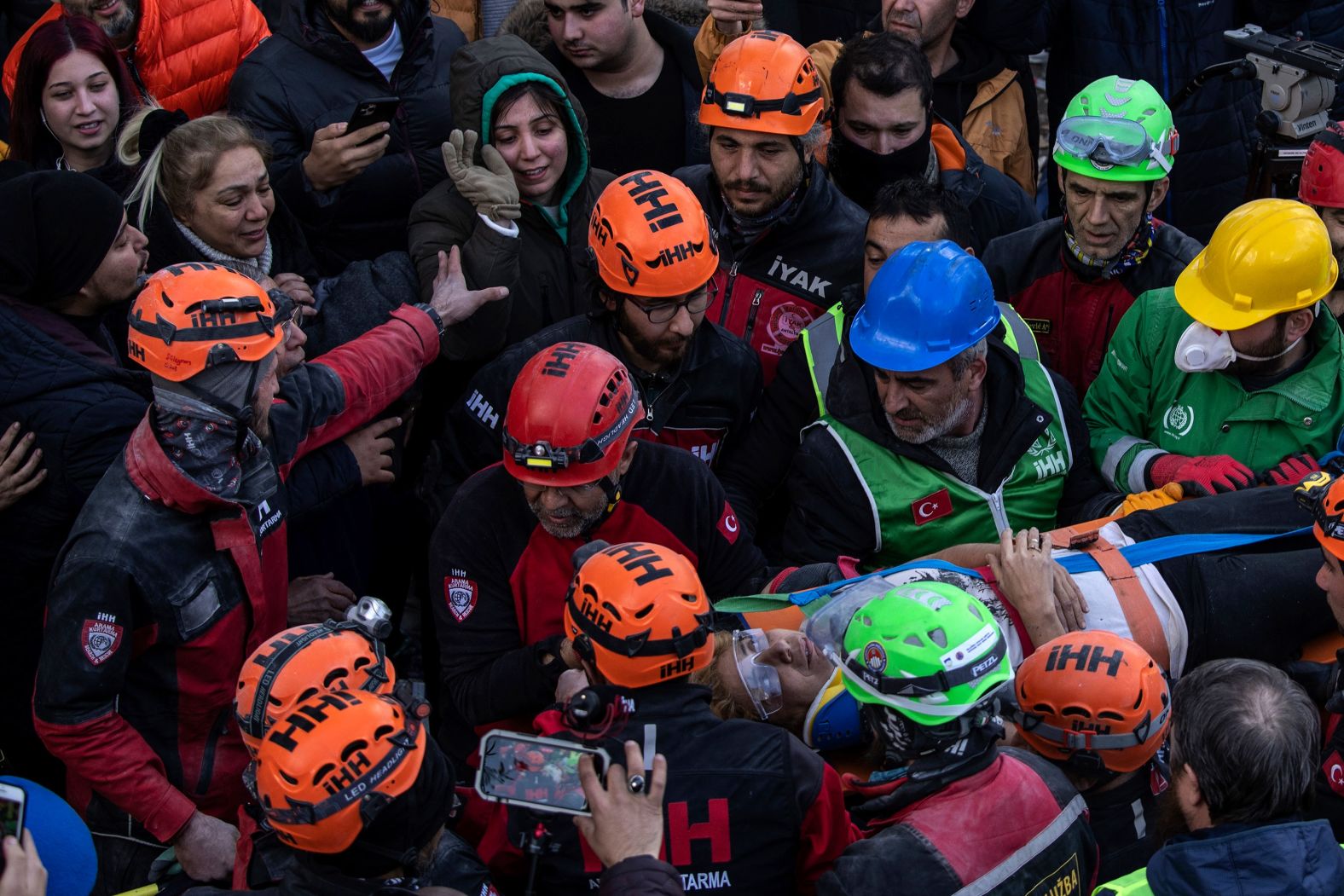 Raziye Kilinc is carried through a crowd on a stretcher after she was rescued from a destroyed building in Iskenderun, Turkey, on February 10. Her daughter is seen waving at the top.