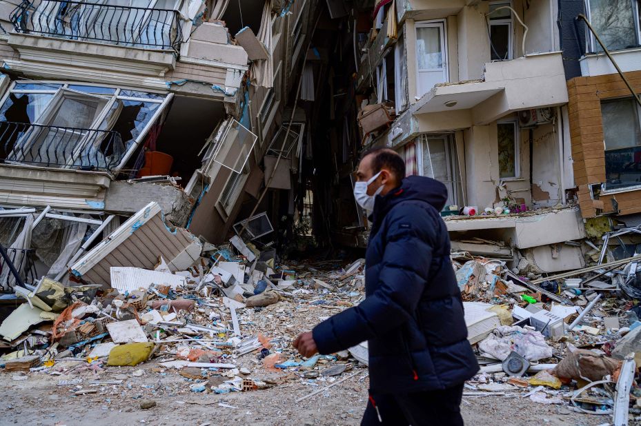 A man walks past collapsed buildings in Hatay on February 10.