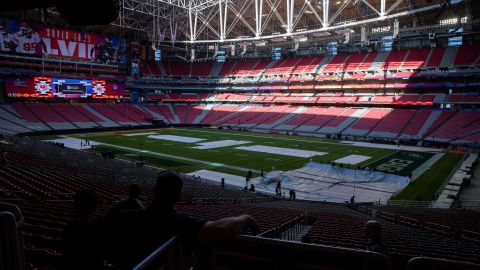 Workers cover the field with a tarp ahead of a rehearsal for the Super Bowl LVII Halftime Show at State Farm Stadium in Glendale, Arizona.