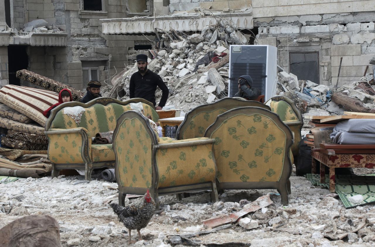 People sit on furniture outside damaged buildings in the rebel-held town of Jandaris, Syria, on February 10.