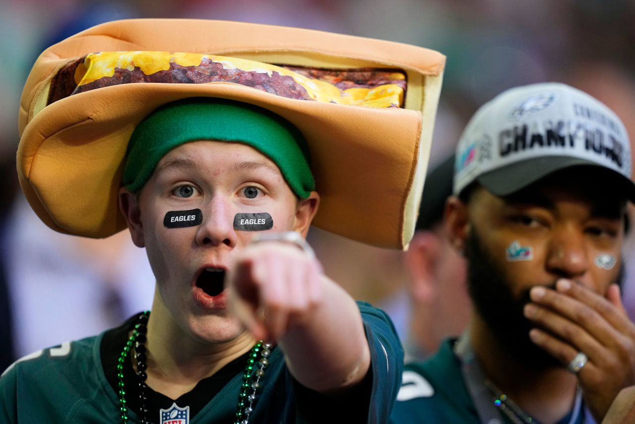 An Eagles fan with a cheesesteak hat gestures at the camera during pregame warmups.