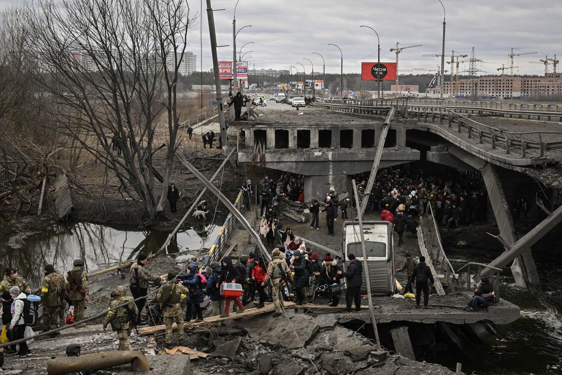 Residents cross a destroyed bridge as they evacuate the city of Irpin, northwest of Kyiv, during heavy shelling and bombing on March 5, 2022.
