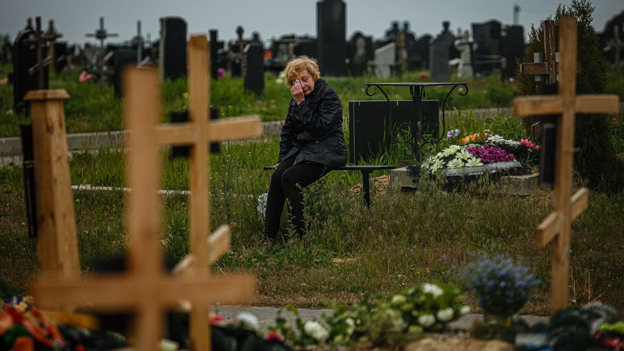 A woman visits the grave of a Ukrainian serviceman, in the military section of a Kharkiv cemetery, May 21, 2022. 