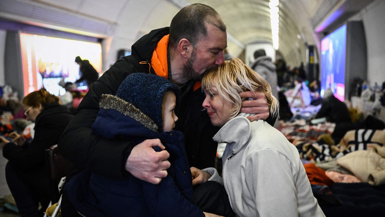 TOPSHOT - Sergyi Badylevych (C), 41, hugs his wife Natalia Badylevych (R), 42, and baby in an underground metro station used as bomb shelter in Kyiv on March 2, 2022. - On the seventh day of fighting in Ukraine Russia claims control on March 2, 2022 of the southern port city of Kherson, street battles rage in Ukraine's second-biggest city Kharkiv, and Kyiv braces for a feared Russian assault. (Photo by Aris Messinis / STF / AFP) (Photo by ARIS MESSINIS/STF/AFP via Getty Images)