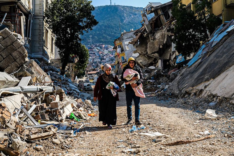 Two people walk through earthquake ruins in Hatay on Sunday, February 12.