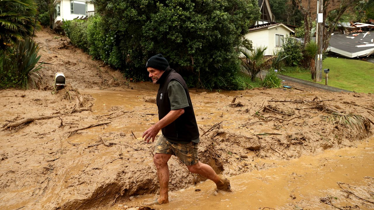 A resident wades through a large landslide on Domain Crescent in Muriwai following Cyclone Gabrielle on February 14.