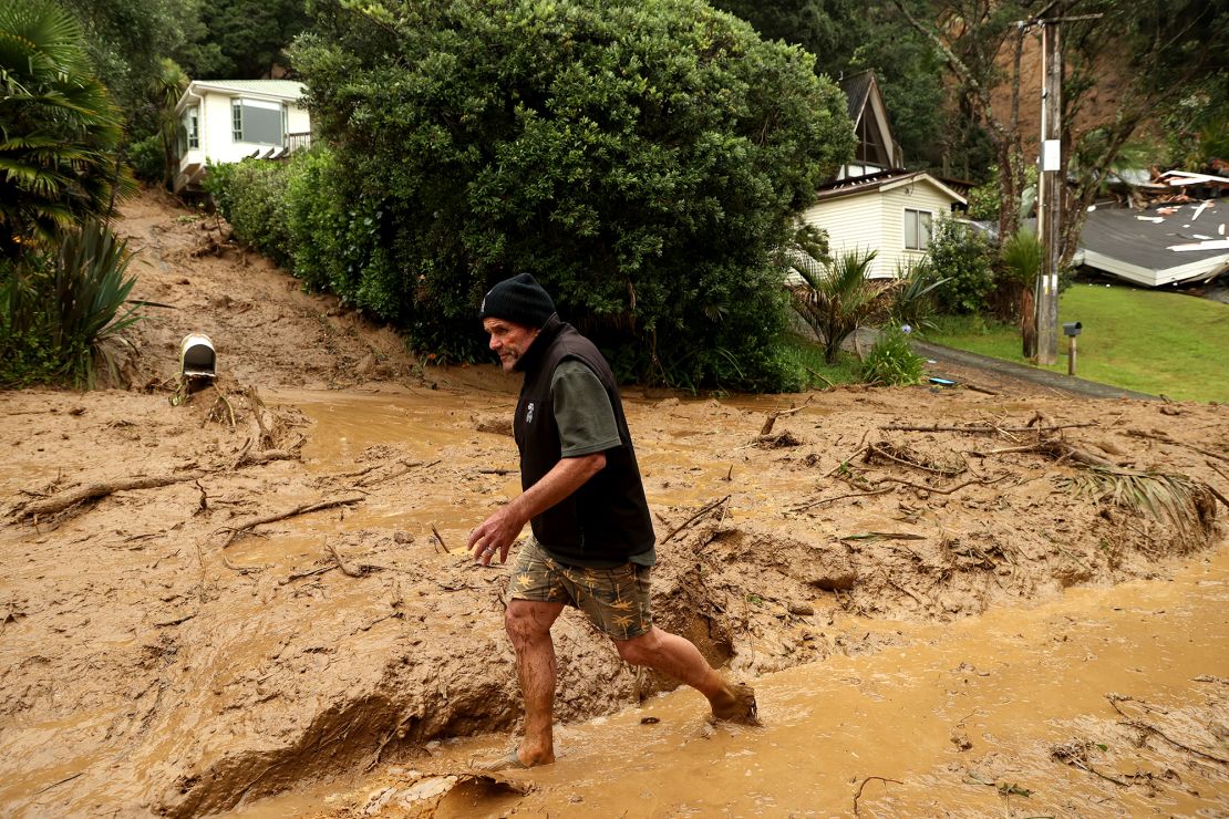 A resident wades through a large landslide on Domain Crescent in Muriwai following Cyclone Gabrielle on February 14.