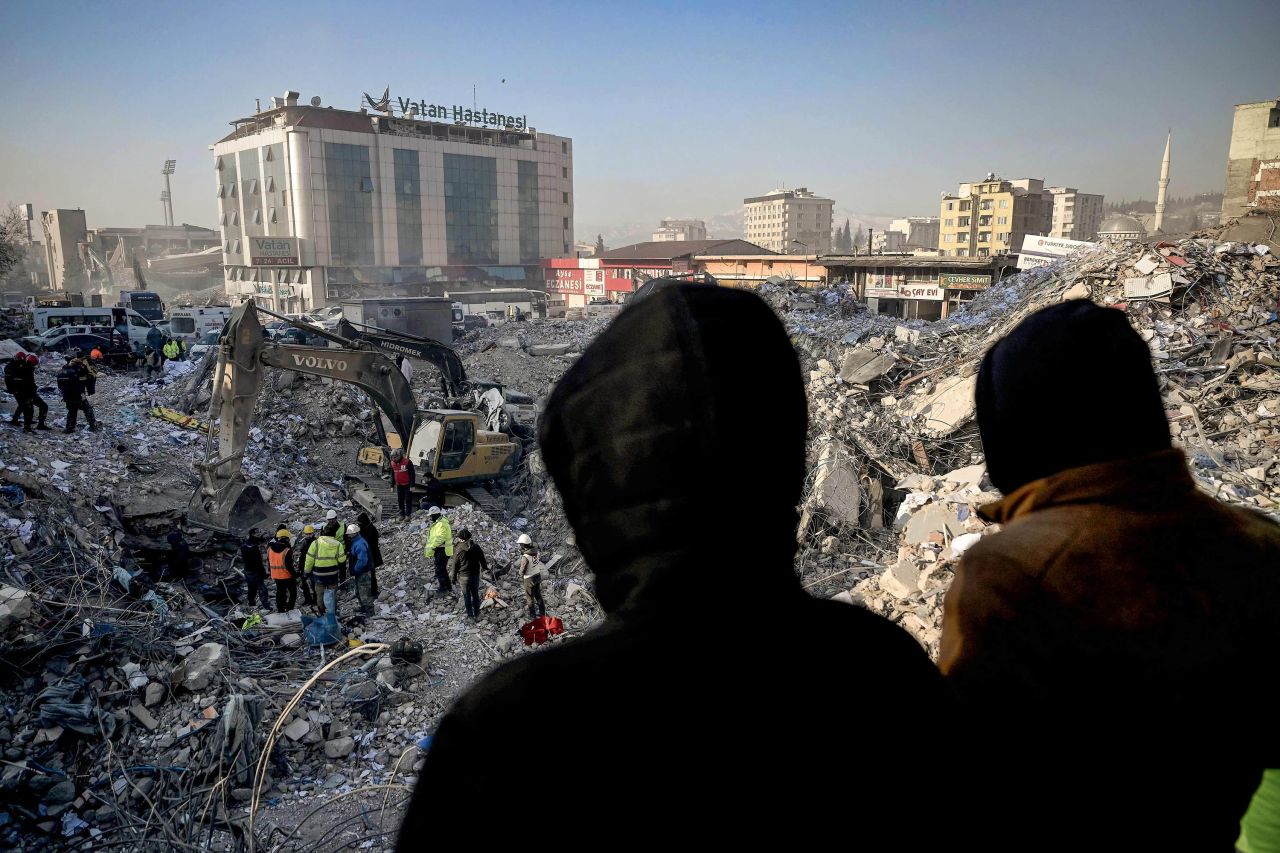 People wait near a collapsed building in Kahramanmaras, Turkey, hoping for news of their missing relatives on Tuesday, February 14.