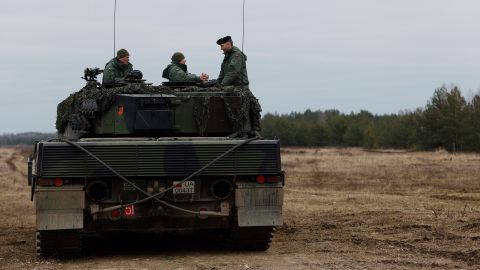 Ukrainian and Polish soldiers sit on top of a Leopard 2 tank during at a military base in Swietoszow, Poland,