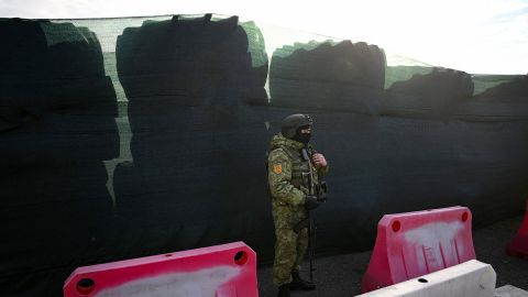 A Belarusian border guard keeps watch and stands by a barricade made of truck tyres at the Divin border crossing point between Belarus and Ukraine in the Brest region on February 15, 2023.