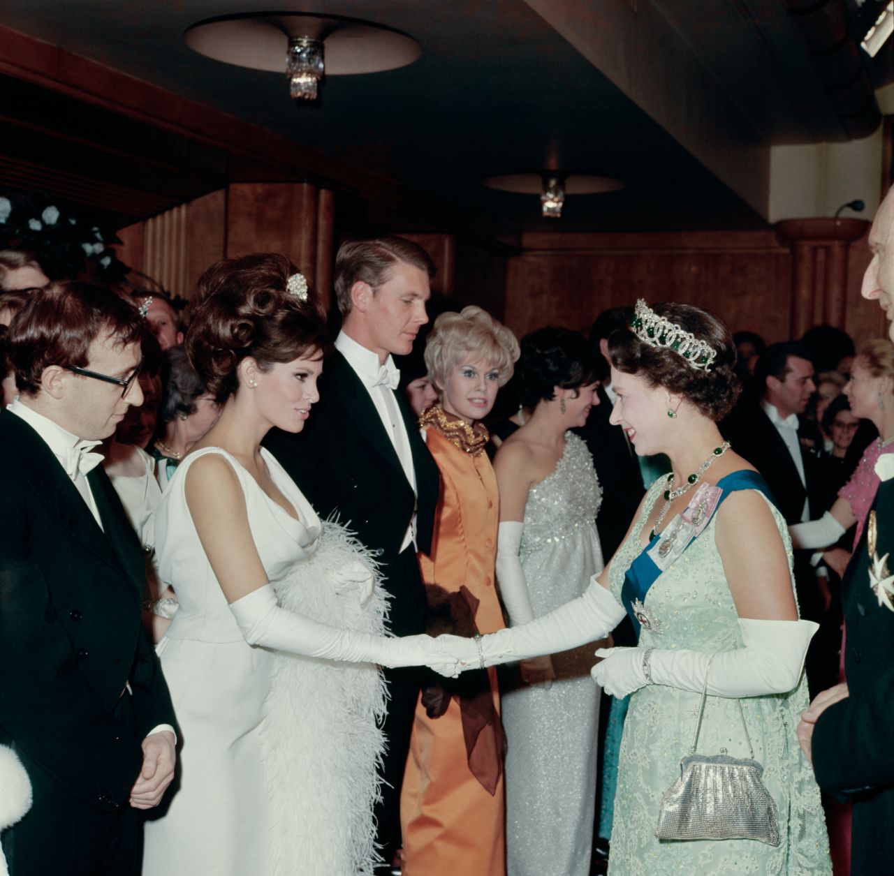 Welch shakes hands with Britain's Queen Elizabeth II at a Royal Film performance in 1966. At left is director Woody Allen.