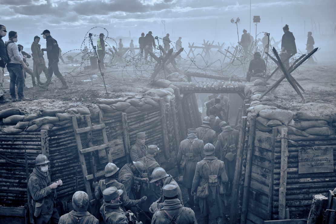 Film crew stand above a trench while the cast mingle below on the set of "All Quiet on the Western Front."
