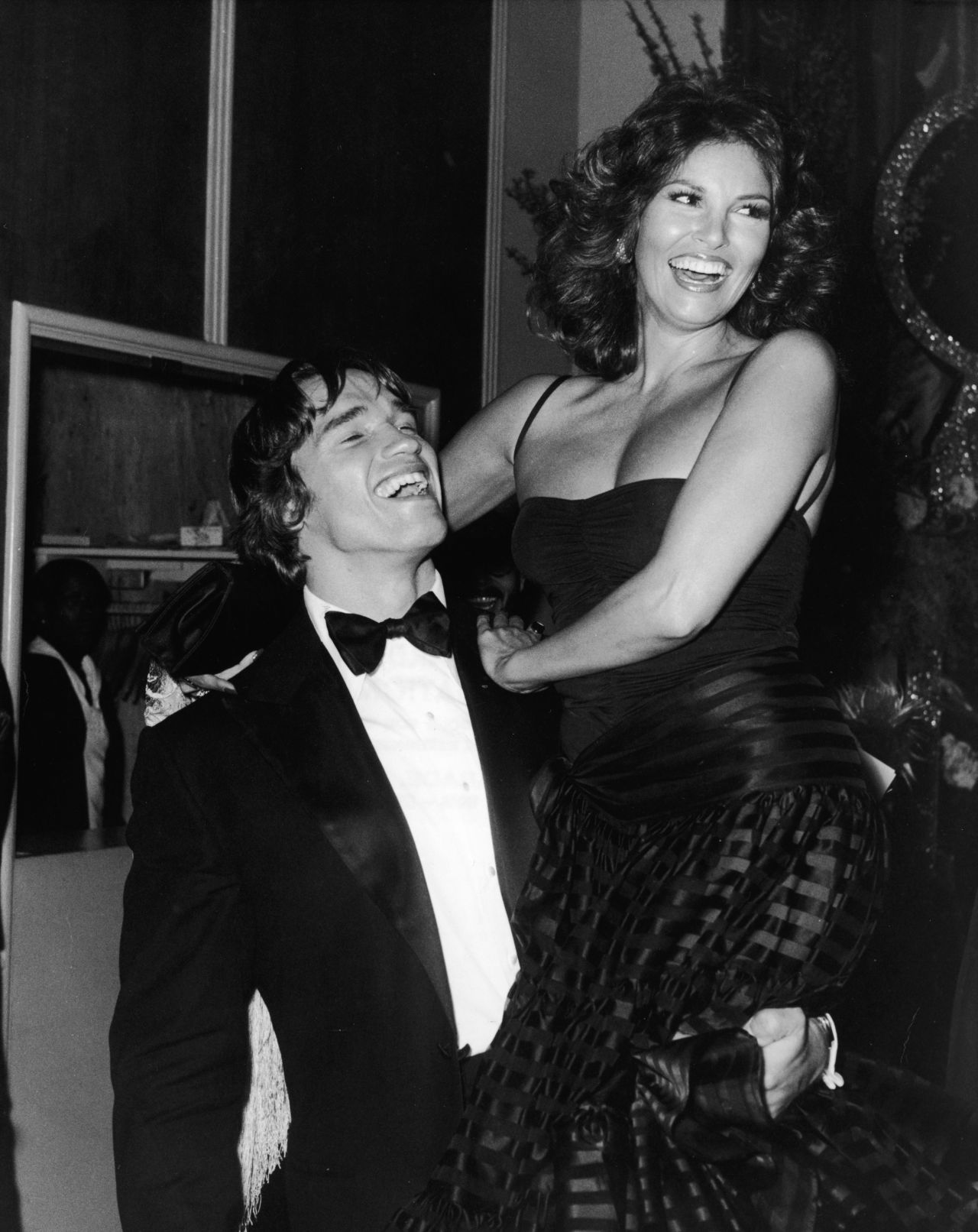 Arnold Schwarzenegger holds up Welch at the Golden Globe Awards in 1977.