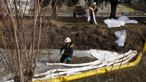Workers place booms in a stream in East Palestine on February 9 as part of the cleanup process after the derailment.