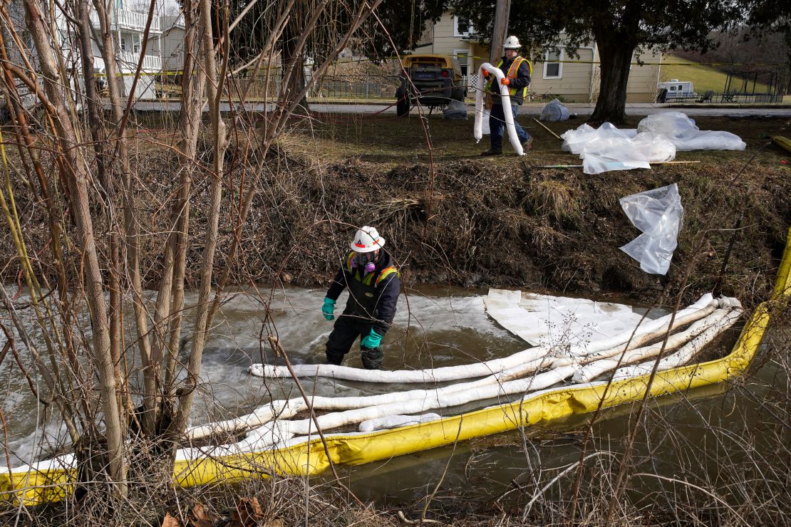 Workers place booms in a stream in East Palestine on February 9 as part of the cleanup process after the derailment.