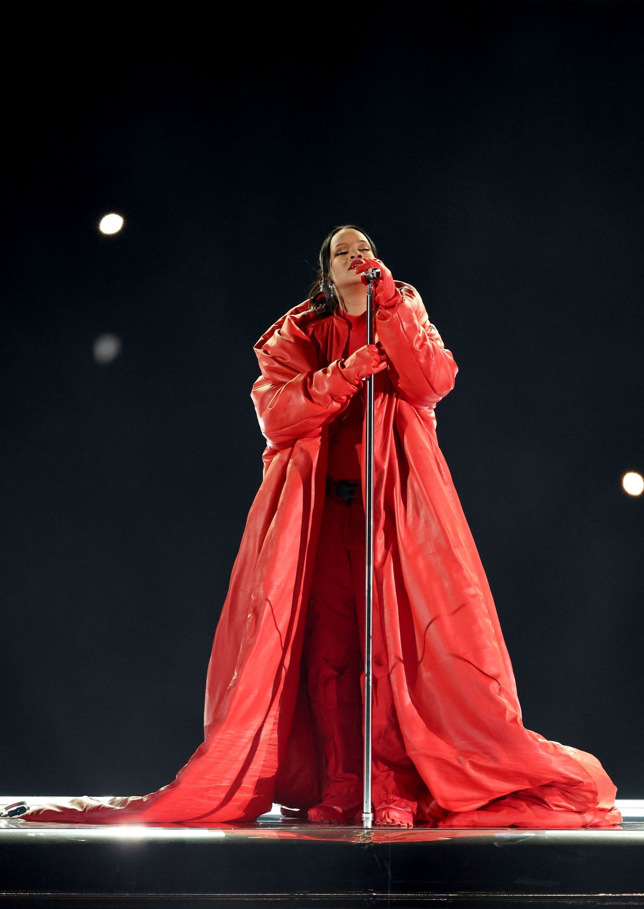 Here comes baby number two! While performing her first Super Bowl halftime show on February 12, Rihanna opted for a firetruck red custom Loewe catsuit and leather corset designed to accentuate her baby bump — announcing to the world she's expecting once again in the most stylish way.