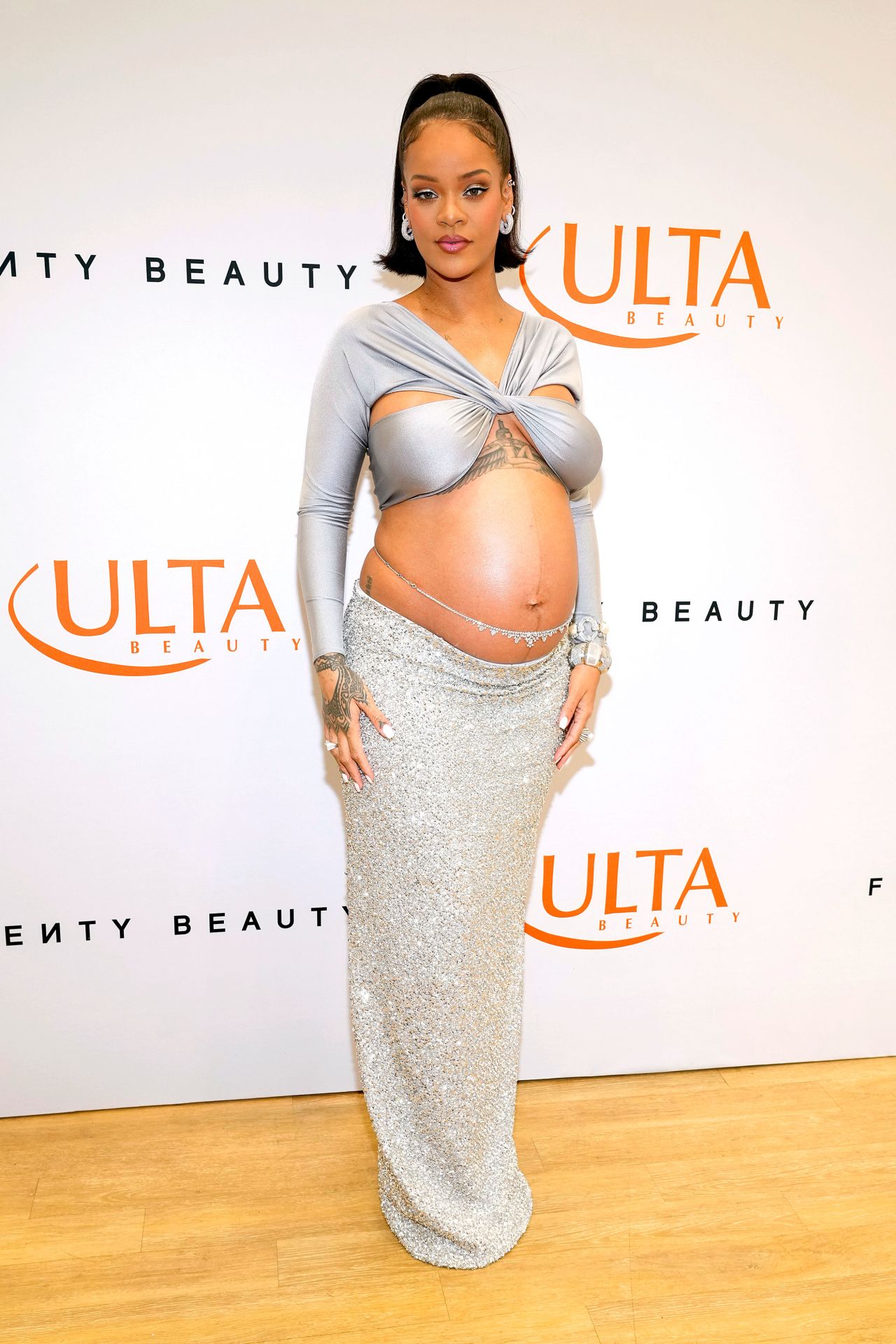 Yet again, batting away the convention that style has to be sacrificed when pregnant, Rihanna arrived at the launch of her makeup brand, Fenty Beauty at ULTA in a custom Coperni silver crop top, glittery column skirt, and matching chain wrapped around her torso.