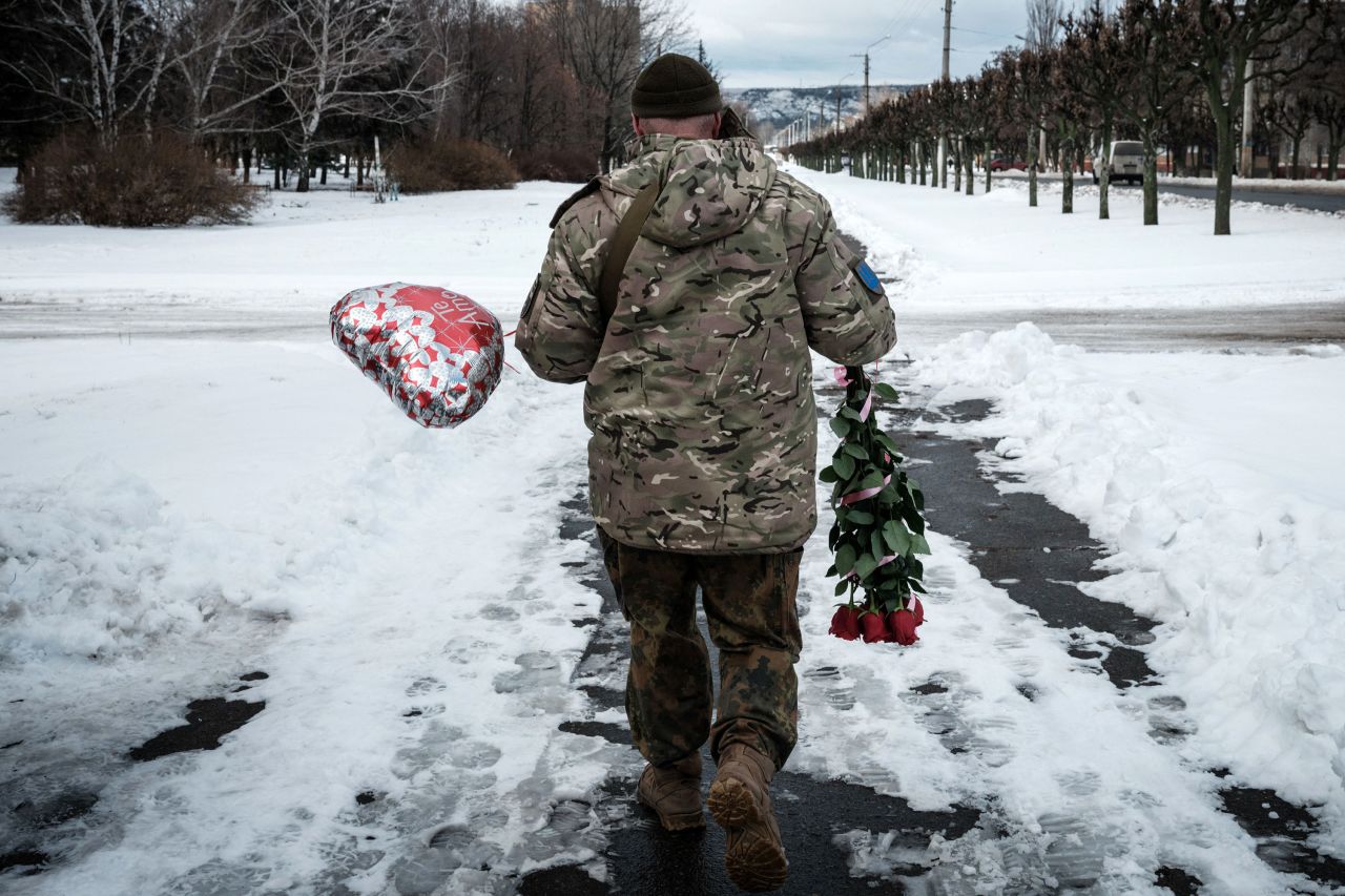 A Ukrainian serviceman in Kramatorsk walks with flowers and a balloon he bought for Valentine's Day on Tuesday, February 14.