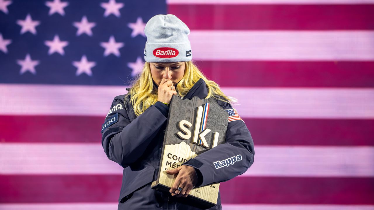Mikaela Shiffrin kisses a medallion with pictures of her father, who died in an accident in 2020.