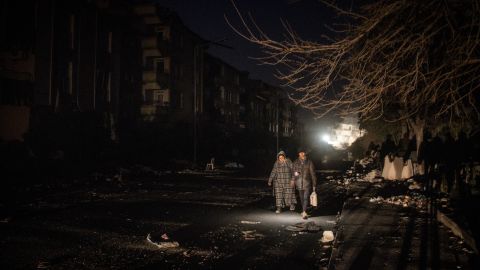 A man and woman walk along a damaged street at night in earthquake- stricken Hatay, Turkey on Thursday.
