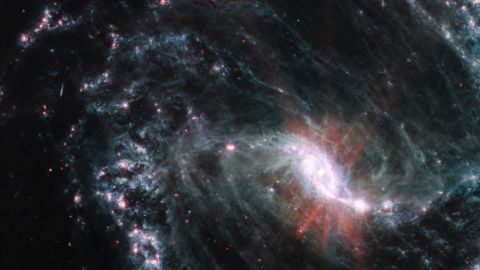 A Webb telescope image of NGC 1365 shows an intricate network of cavernous bubbles and shells as young stars release energy into the galaxy's spiral arms.