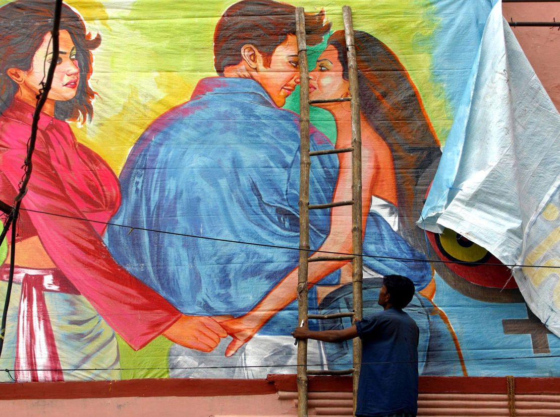 A movie theater worker removes a poster of the 2004 Hindi film "Girlfriend" after outrage from far-right Hindu groups. 