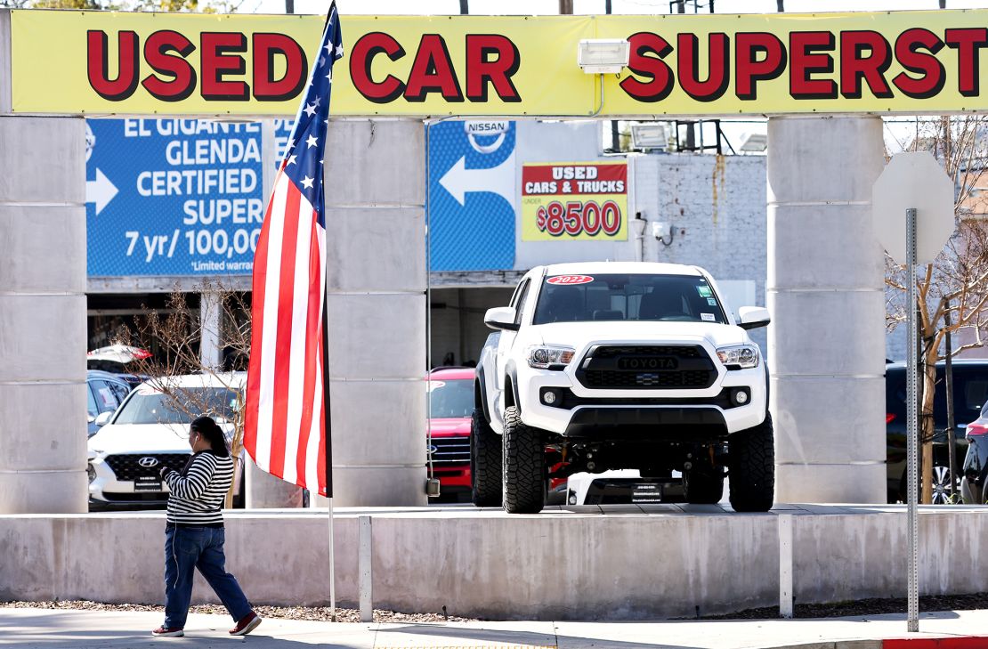 A pedestrian walks past a used car lot on February 15, 2023 in Glendale, California.