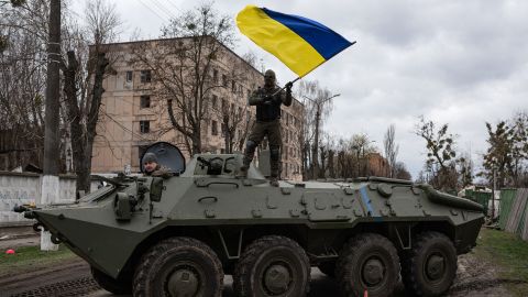 Un soldado ucraniano ondea la bandera nacional de su país mientras está parado en un vehículo de combate de infantería en Hostomel en abril pasado.