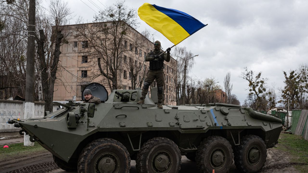 A Ukrainian soldier waves his country's national flag while standing on top of an armored personnel carrier last April in Hostomel.
