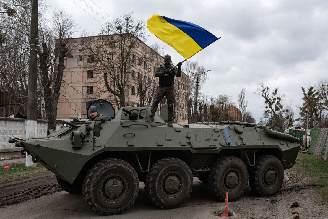 A Ukrainian soldier waves his country's national flag while standing on top of an armored personnel carrier last April in Hostomel.