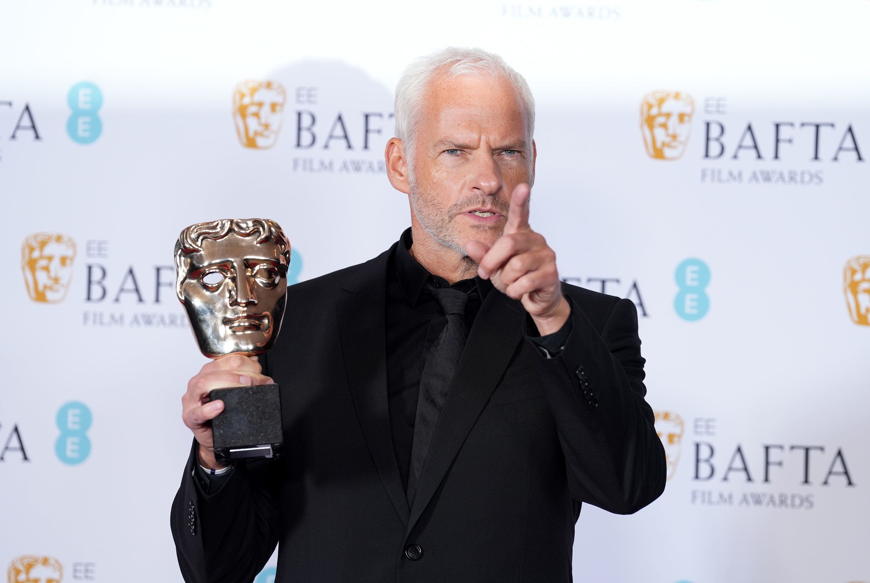 Martin McDonagh poses with his original screenplay award for The Banshees of Inisherin.