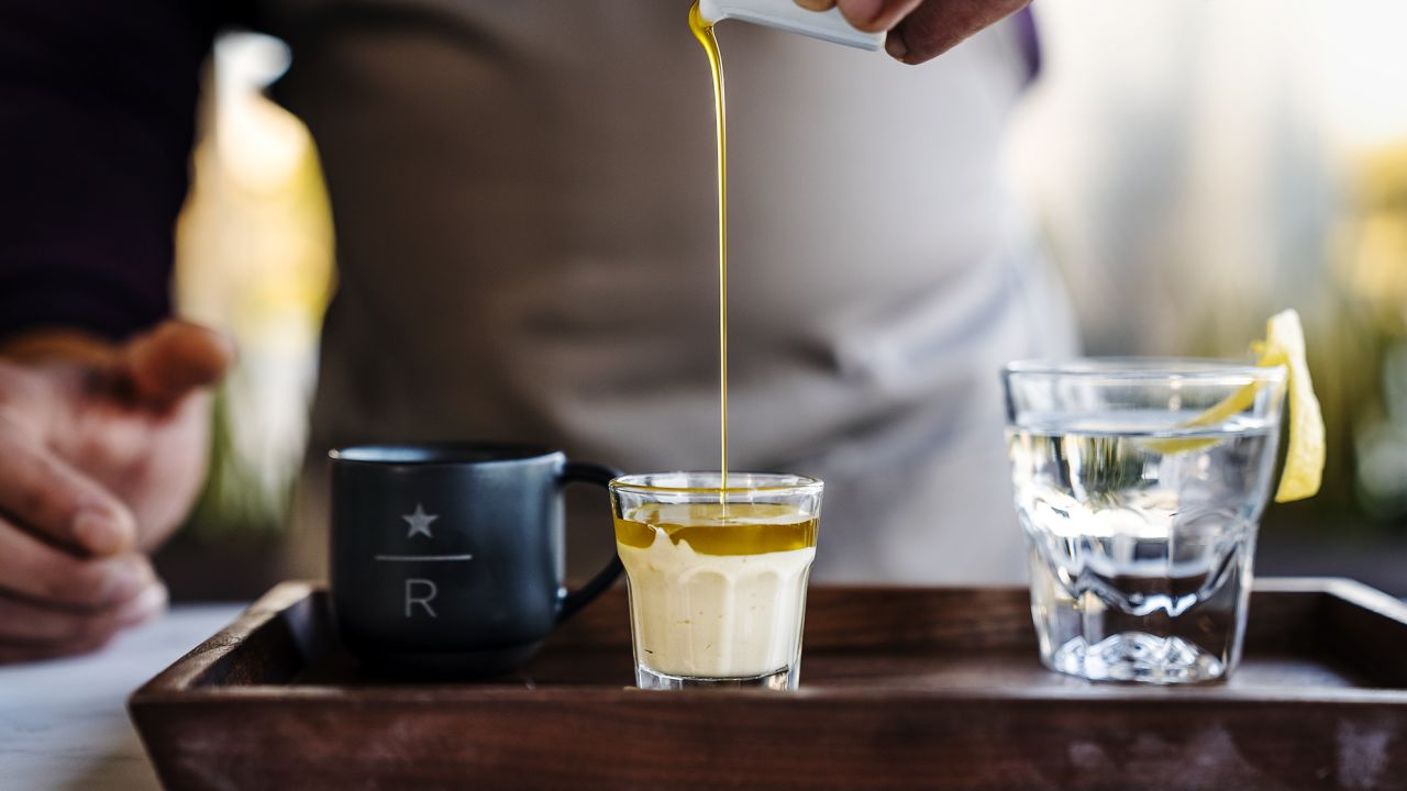 A barista pours extra virgin olive oil into a passion fruit cold foam before mixing in espresso.