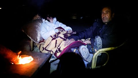 A father sits with his children as they seek shelter outside in Antakya in Hatay province, Turkey on Monday.