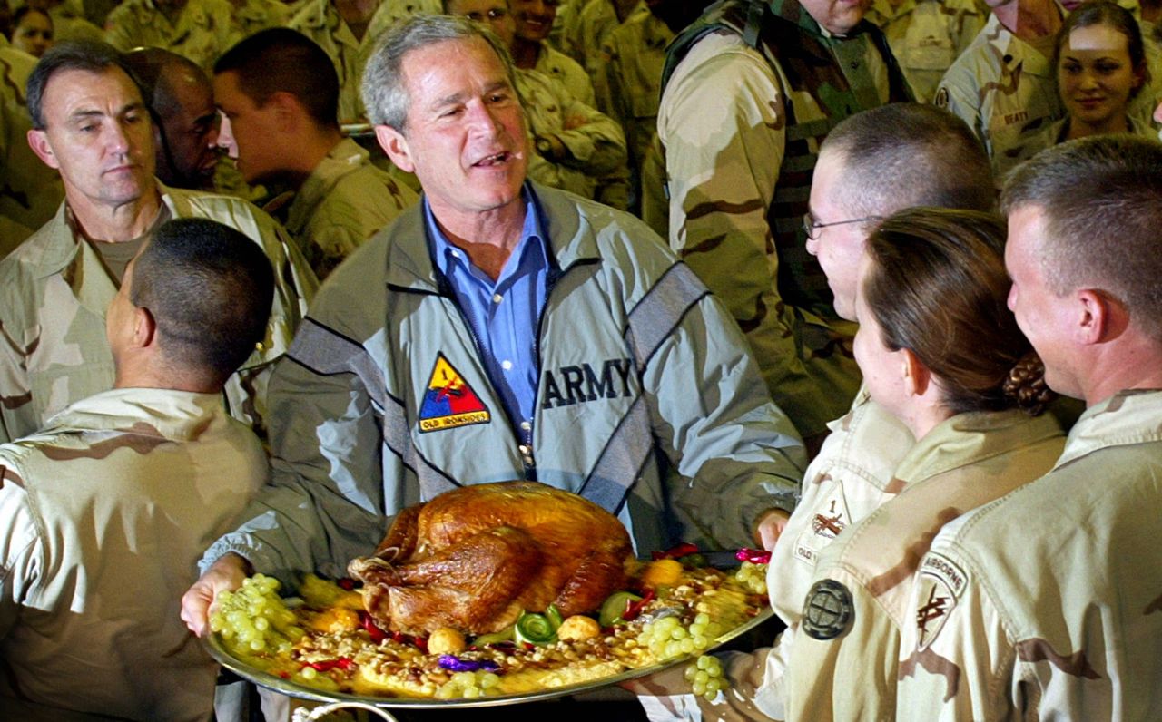 President George W. Bush holds a Thanksgiving turkey while visiting US troops stationed in Baghdad, Iraq, in November 2003. The Iraq War began in March of that year.