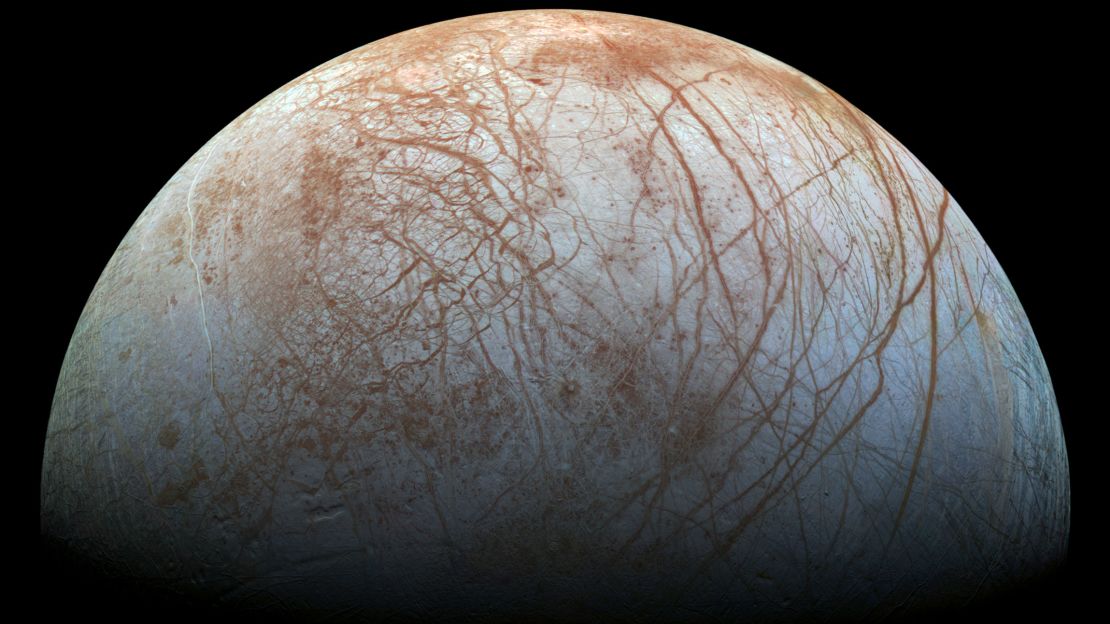 Jupiter's moon Europa hosts a subsurface ocean beneath a thick shell of ice, which bears a series of red streaks.