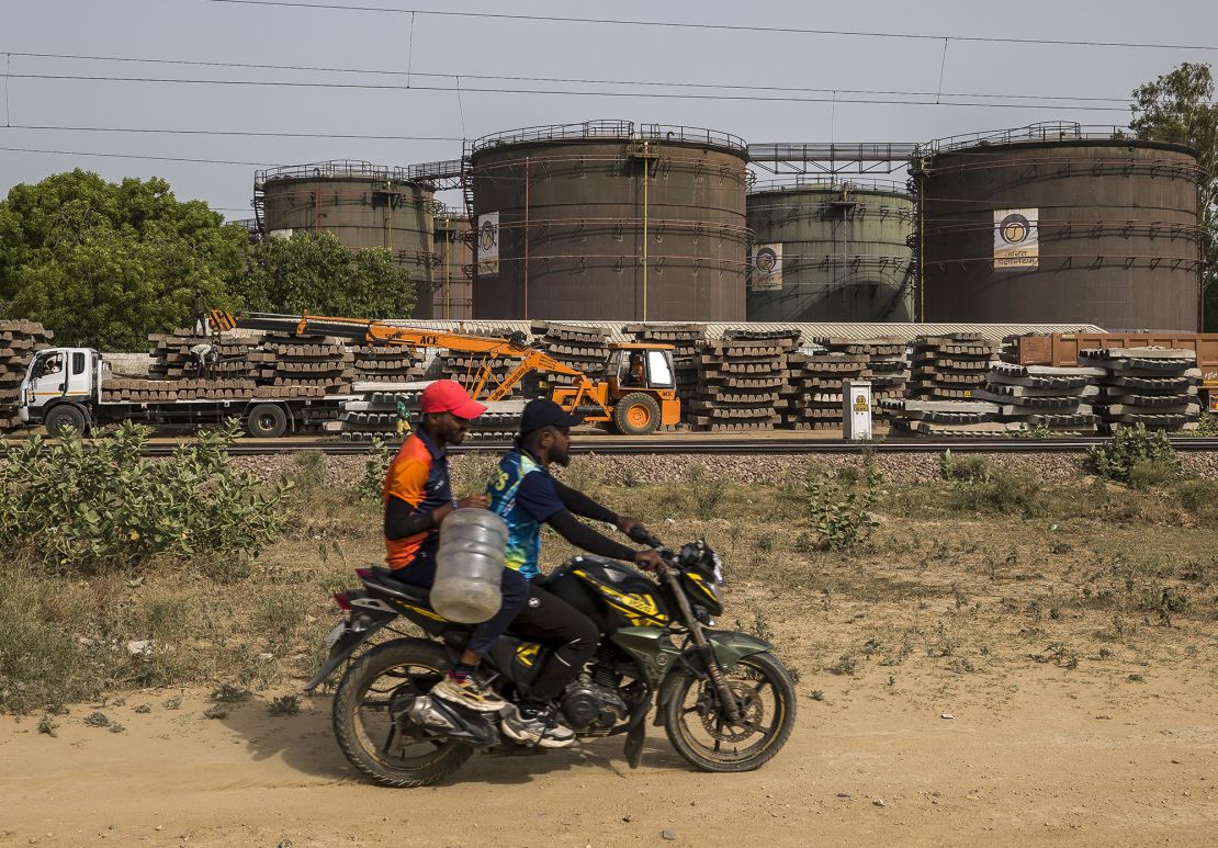 A motorcyclist rides past an oil depot in New Delhi, India, on Sunday, June 12, 2022.