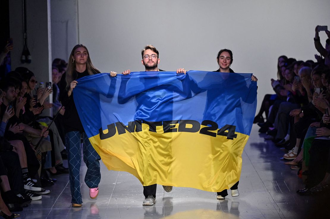 Ukrainian fashion designers Ksenia Schnaider, Ivan Frolov and Julie Paskal wave a Ukraine's flag as they opened a dedicated Ukrainian runway event on the final day of London Fashion Week.