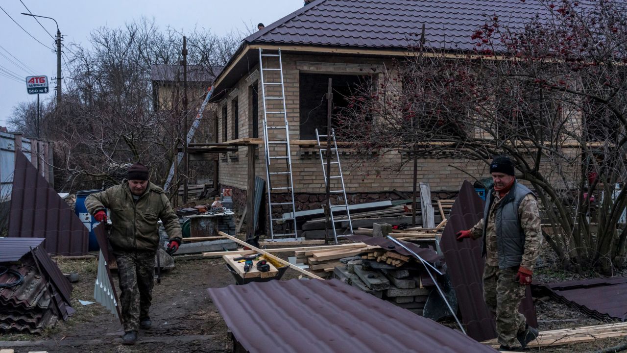 Workers cut pieces of roofing as they repair the house belonging to Kostiantyn Momotov, which was among those destroyed last year in Bucha.
