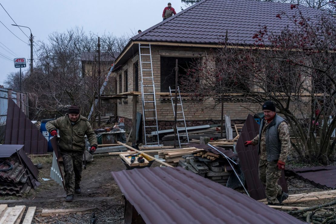 Workers cut pieces of roofing as they repair the house belonging to Kostiantyn Momotov, which was among those destroyed last year in Bucha.