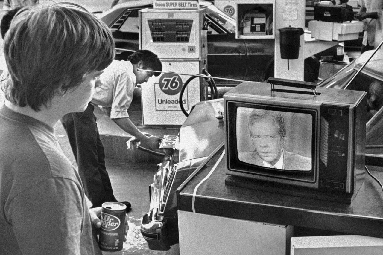 FILE - In this July 15, 1979 file photo, college student Chuck McManis watches President Jimmy Carter's nationally televised energy speech from a service station in Los Angeles, as a gas station attendant fills up a customer's car. On Wednesday, Aug. 12, 2015, Carter announced he has cancer and will undergo treatment at an Atlanta hospital. (AP Photo/Mao, File)