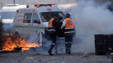 Medics run through tear gas as they evacuate a wounded Palestinian individual during clashes with Israeli forces on Wednesday.