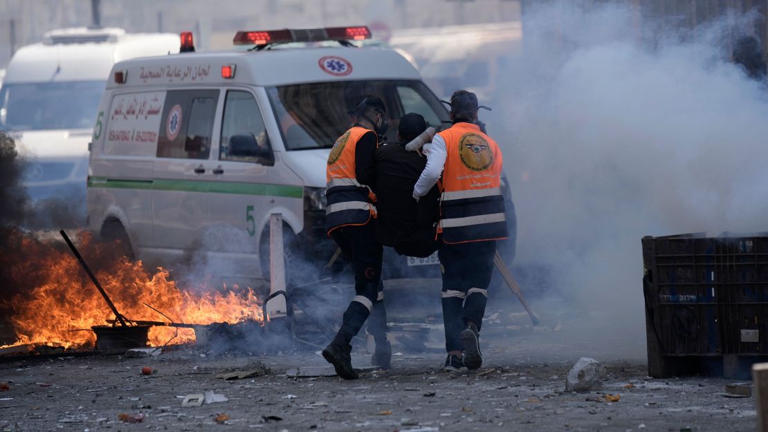 Medics run through tear gas as they evacuate a wounded Palestinian individual during clashes with Israeli forces on Wednesday.