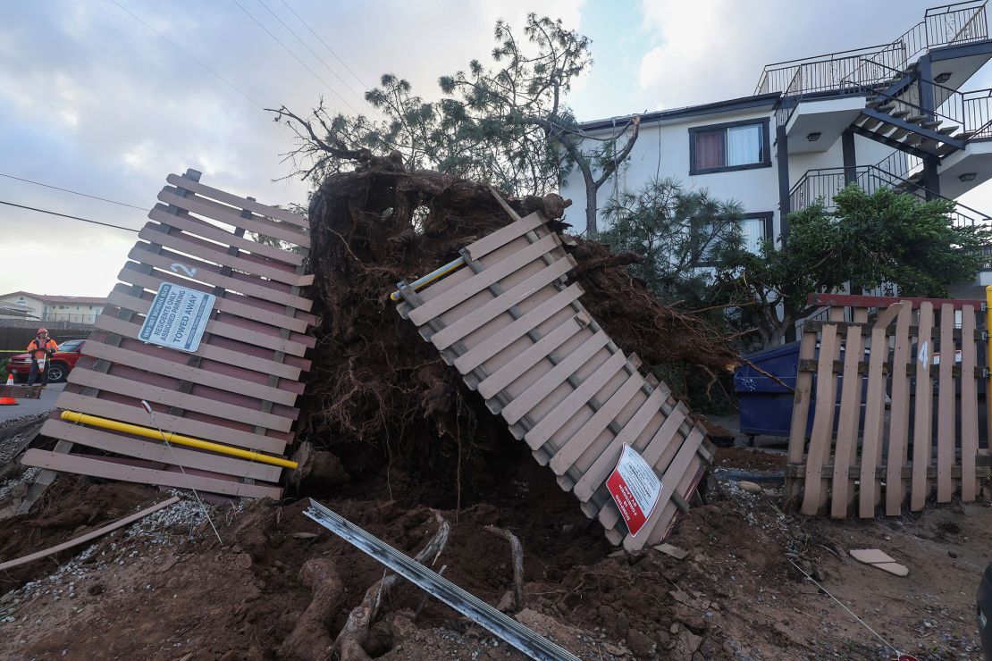 A damaged fence is seen after a large tree was blown into an apartment building during a winter storm in San Diego, California, on Tuesday, February 22.