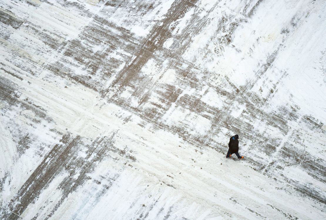 A man crosses a snow-covered street in downtown Minneapolis on February 22, 2023.