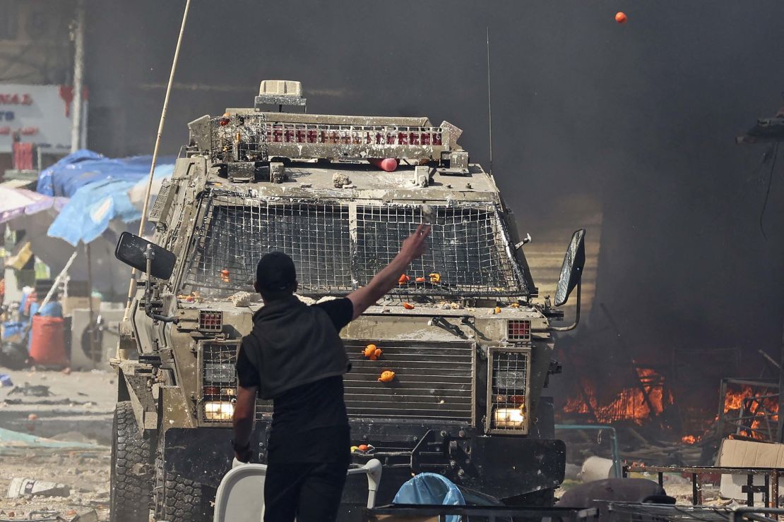 A Palestinian faces an Israeli military vehicle during a raid on the West Bank city of Nablus, on February 22, 2023. 