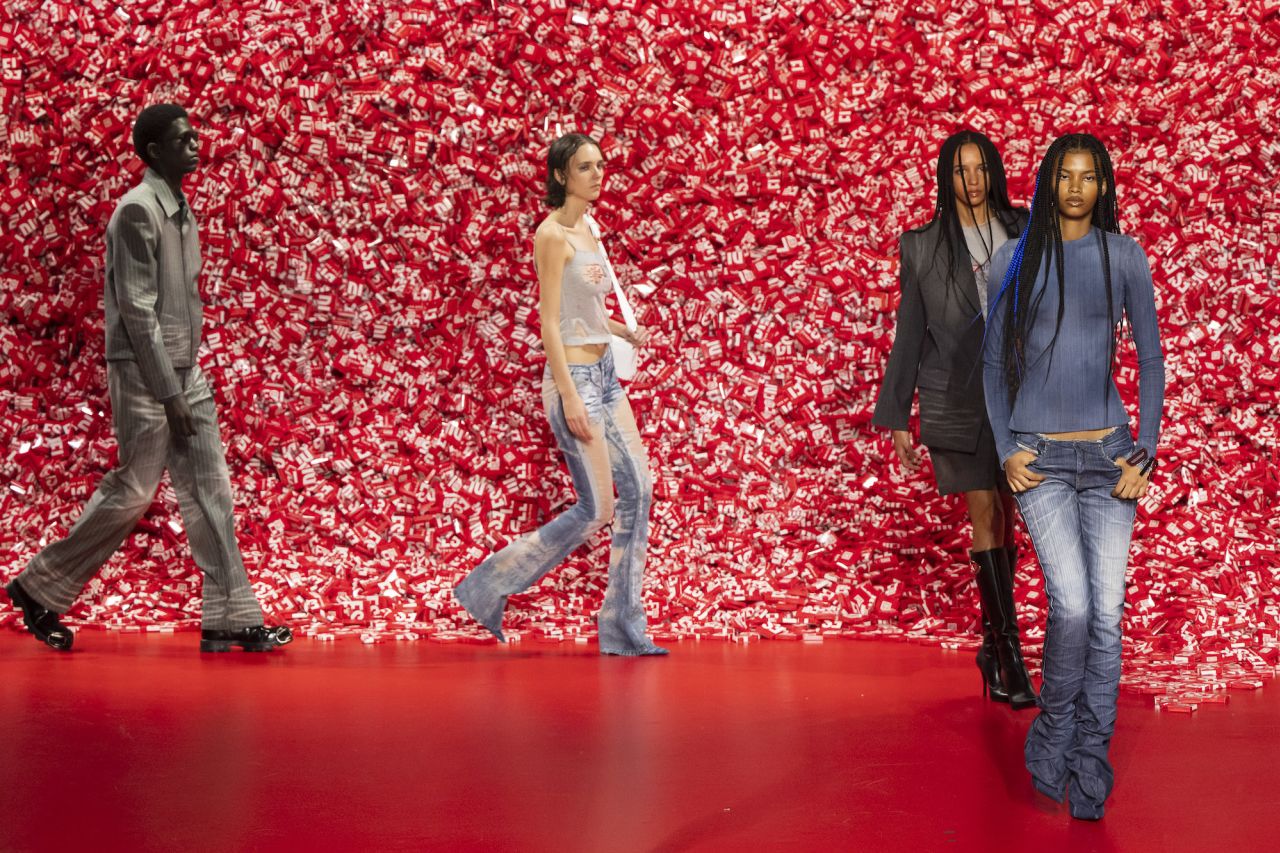 Models walk pass the 'mountain' of bright red condom boxes.