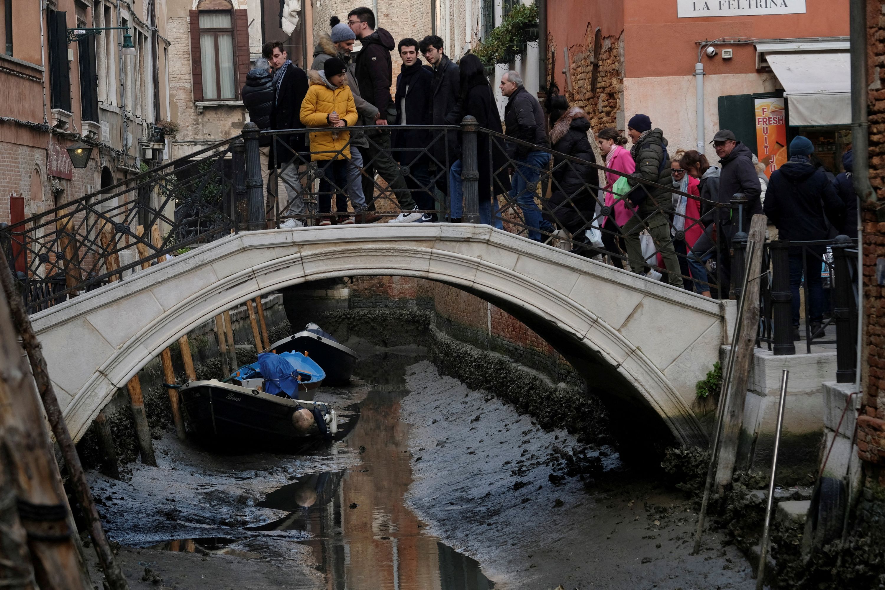 People look at a dried-up canal in Venice, Italy.