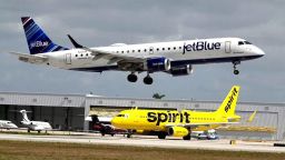 A JetBlue airliner lands past a Spirit Airlines jet on taxi way at Fort Lauderdale Hollywood International Airport on Monday, April 25, 2022, in Florida. Spirit has urged its shareholders to reject a hostile takeover offer from the New York-based carrier over federal antitrust concerns.